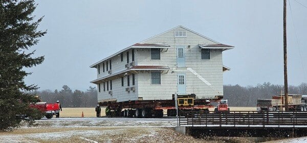 World War II-era barracks in Ft McCoy being moved on a flat bed trailer